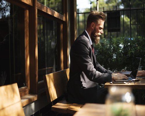Person working comfortably on a laptop by a bright window