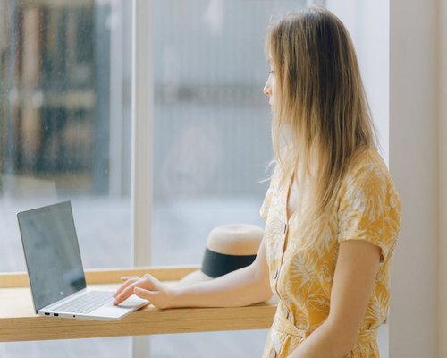 Woman looking out the window taking a break from her laptop